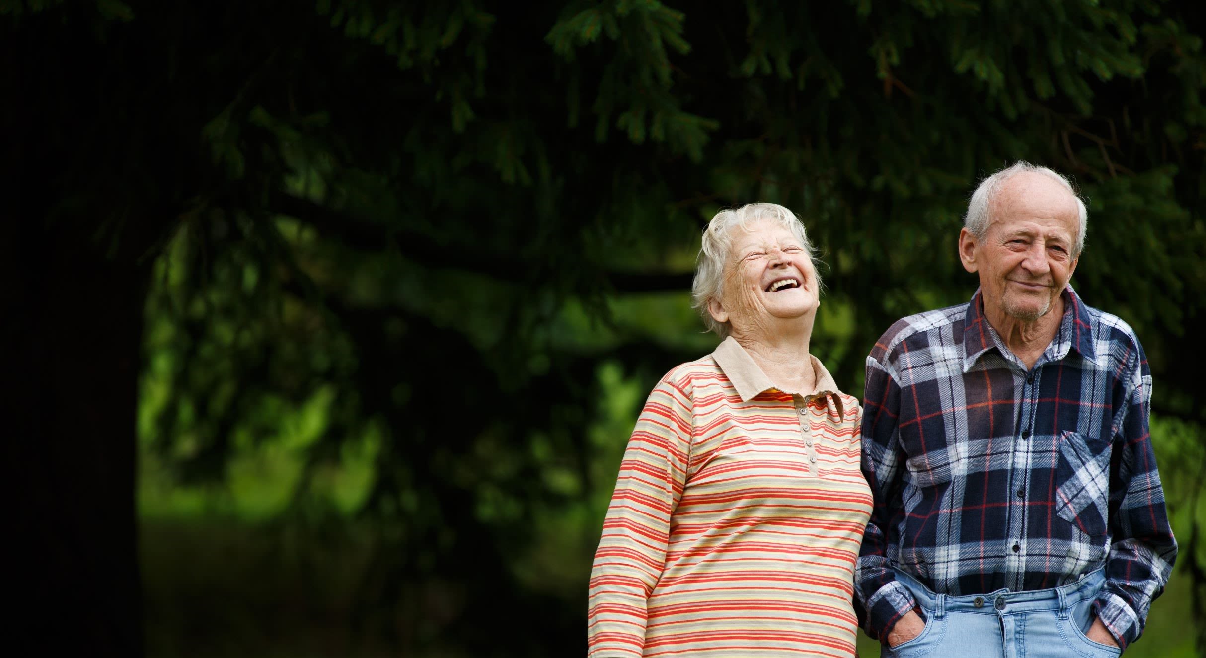 An older couple laughing together outdoors An older couple laughing together outdoors
