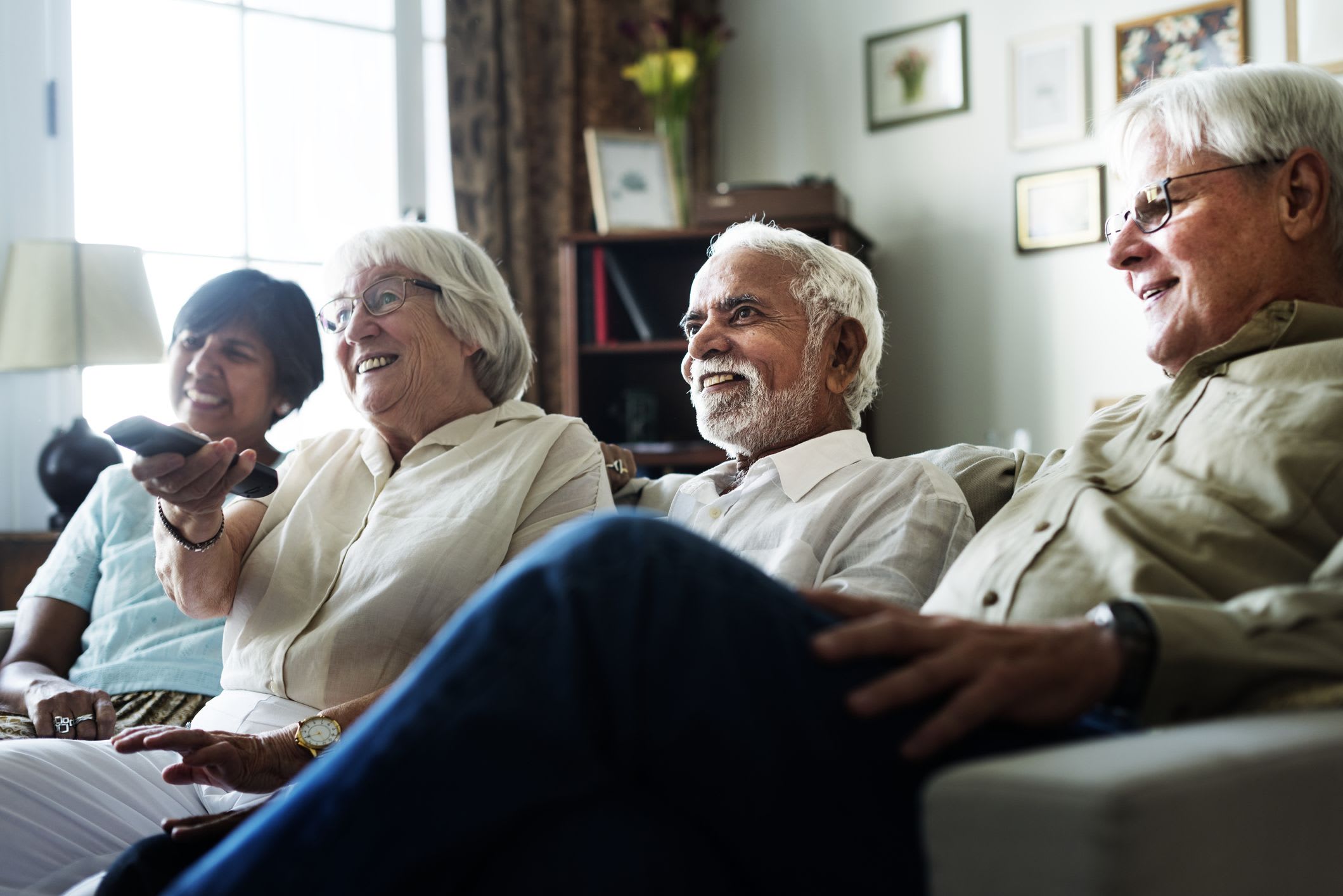 Four older adults sitting together in a living room